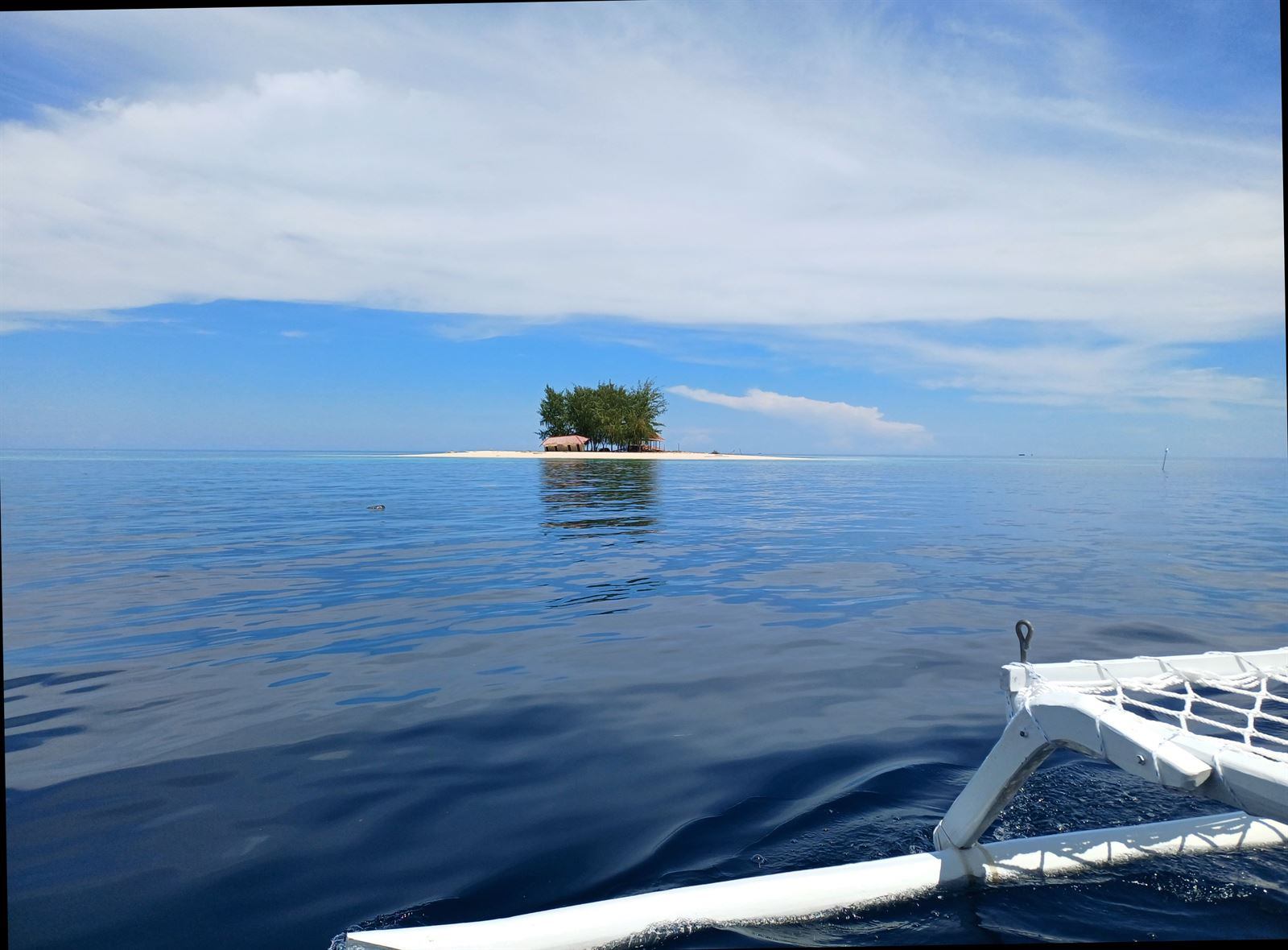 A single palm-topped islet on a flat calm sea